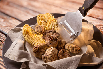 Alba white truffles in napkin with raw egg tagliolini and steel truffle cutter on wooden background - obrazy, fototapety, plakaty