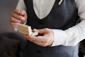 man hold in hand gold wedding rings in wooden box close up portrait.  groom in grey suit holds wedding ring of white gold on palm on background. wedding ceremony. wedding day. bride and groom