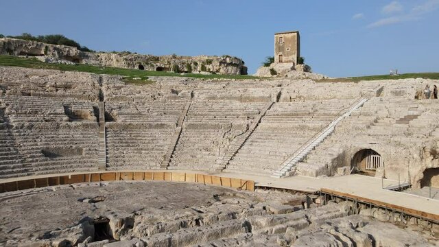 Amazing Aerial shot of inside the Roman amphitheater of Syracuse Sicily, archeological park with the ancient ruins.