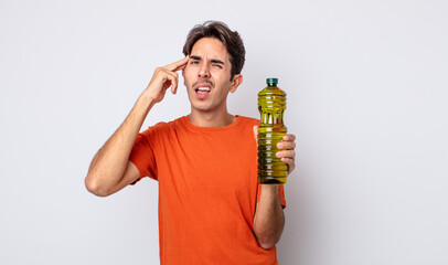 young hispanic man feeling confused and puzzled, showing you are insane. olive oil concept