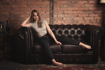 Fototapeta na wymiar beautiful girl on a sofa made of black leather.tinted photo