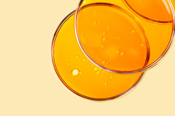 Top view of petri dishes with cosmetic oil inside.Yellow background with copy space.