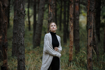 a girl in a white sweater walks in the autumn forest
