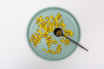 A lot of vitamin D3 on a plate, a few capsules in a spoon