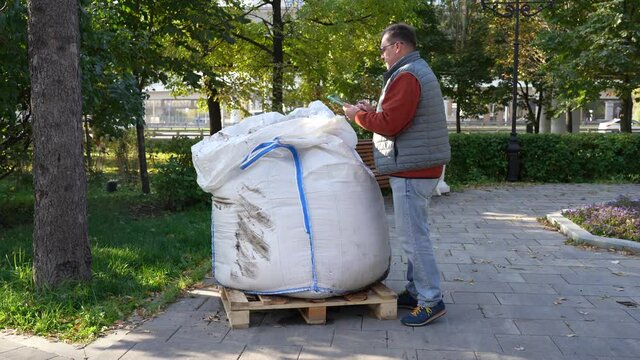 Man with a tablet checks the quality of the contents of a large white bag