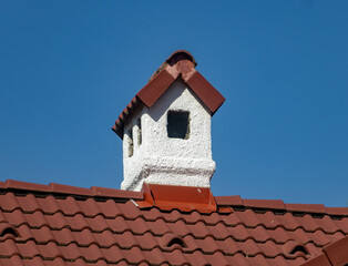 A white chimney on the roof of red tiles