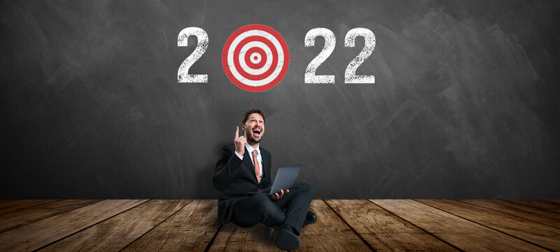 businessman sitting in front of a blackboard with the message 2022 and target symbol