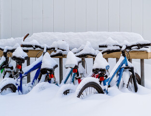 Bicycles  in a outdoor bike rake buried in winter snow