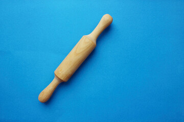 A rock for a test made of wood on a blue background. Cooking and baking. cookery. View from above. Copy space. The scayth for the test is crushed on the left.