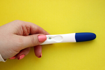 woman hand holding a negative pregnancy test on a yellow background. Motherhood, Pregnancy, Happiness, Children, The Concept of Birth Control. Health problems and problems with conception. Copy space