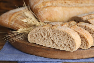 Cut delicious ciabatta on wooden board, closeup