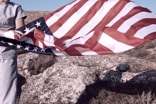 An unrecognizable boy holding waving US flag, beeng a patriot concept