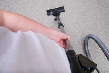 A person vacuuming the carpet in the house, cleaning rug with the vac concept