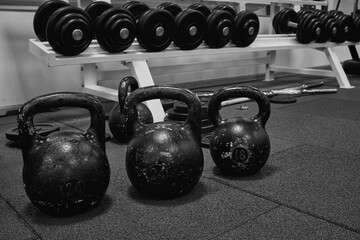 Naklejka na ściany i meble Bodybuilding equipment. kettlebells on rubber floor in the gym. Fitness or bodybuilding concept background. black and white photography