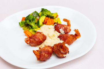 Camarones envueltos con tocino y rellenos de queso con puré de papa y verduras