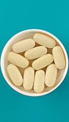 yellow dietary supplement pills on turquoise background. dietary supplement vertical close-up