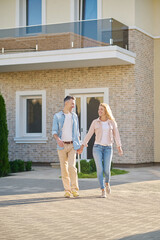 Smiling man and woman walking holding hand