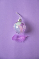 glass Christmas feather filled decoration ball against purple background
