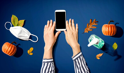 Smartphone with a mask and a sanitizer bottle in Autumn