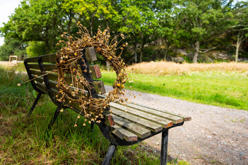 Dried flower wreath hanging on a bench in a park.