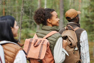 Back view of three young people walking in forest in row while enjoying hiking trail, copy space