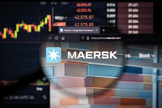 Maersk company logo on a website with blurry stock market developments in the background, seen on a computer screen through a magnifying glass