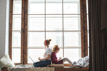 Two sisters study at home. The girl writes in a notebook. Children in headphones.