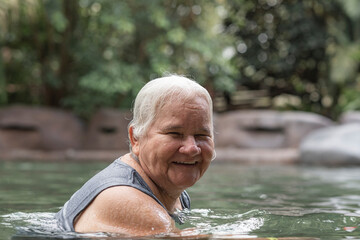 Mujer mayor disfrutando de una piscina de aguas termales muy feliz - obrazy, fototapety, plakaty