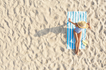 Woman sunbathing on beach towel at sandy coast, aerial view. Space for text