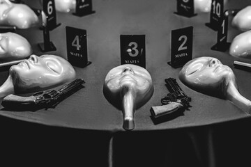 Mafia game the mask and gun on table. Black and white color filter. Game tournament concept.