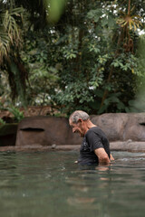 Fototapeta na wymiar Hombre anciano con cabello canoso disfrutando en una piscina de agua termal