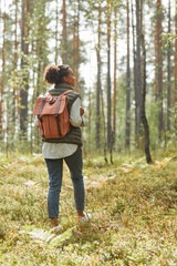 Full length back view portrait of young African-American woman with backpack enjoying hiking in...