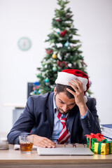 Young male employee celebrating Christmas at workplace