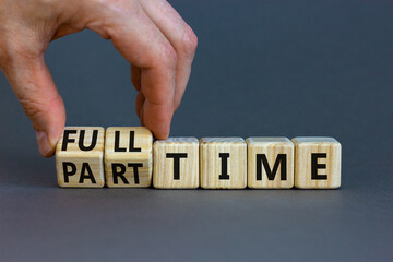 Full or part time symbol. Businessman turns wooden cubes and changes words 'full-time' to 'part-time'. Beautiful grey table, grey background. Business,fFull or part time concept. Copy space.