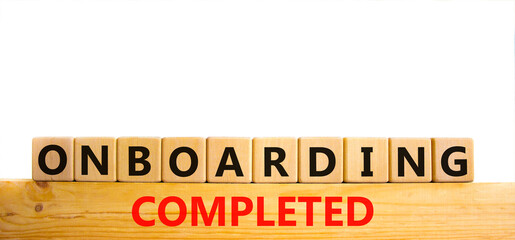 Onboarding completed symbol. Words 'Onboarding completed' on wooden cubes. Business and onboarding completed concept. Beautiful wooden table, white background. Copy space.
