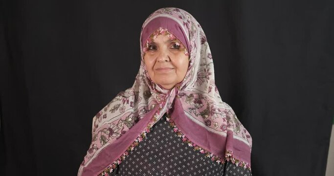 Portrait of hijab, old senior woman on black background. Turkish woman is happy with scarf.