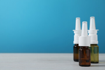 Bottles of nasal sprays on white wooden table. Space for text