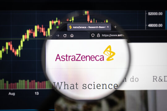 AstraZeneca company logo on a website with blurry stock market developments in the background, seen on a computer screen through a magnifying glass