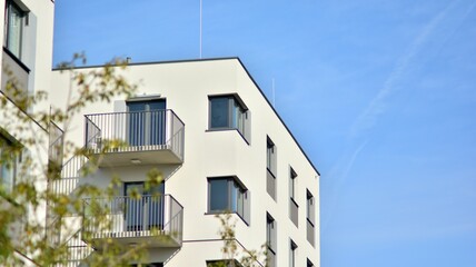 Inspiring view of the modern city. The wall of the apartment building   against trees. Apartment construction and ecology, view of  modern  building with blue sky and green tree. Sunlight