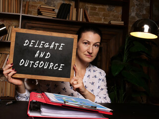 Business concept about DELEGATE AND OUTSOURCE with sign on the board