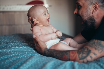 Tattooed bearded father playing with his son