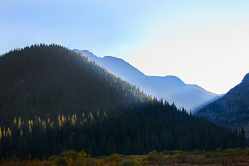 Fototapeta premium Beams of sun hitting desert mountains covered in pine trees