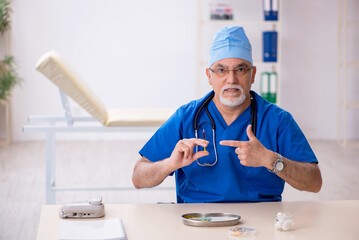 Old male doctor working in the clinic