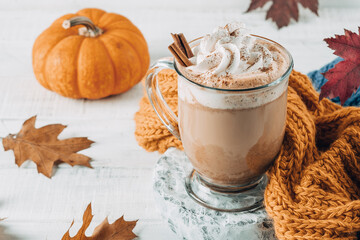 Pumpkin spice latte in a glass mug with cinnamon with Autumn decoration
