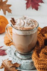Pumpkin spice latte in a glass mug with cinnamon with Autumn decoration