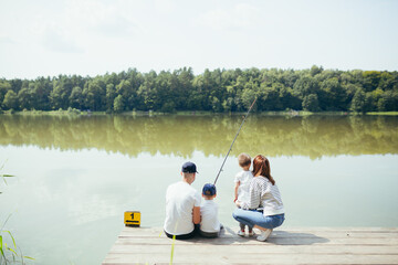 Young family, woman man and two small children fishing on the lake, husband and wife spend a happy weekend together