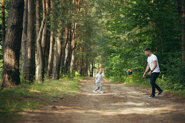 man with little son playing football together digging ball in forest spend time together having fun weekend