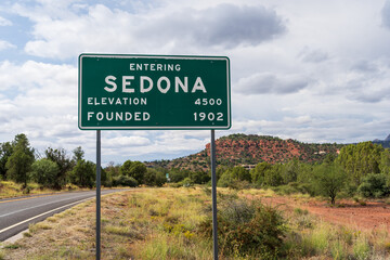 Entering Sedona Elevation 4500 and Founded 1902 sign with road and landscape in soft focus behind - obrazy, fototapety, plakaty
