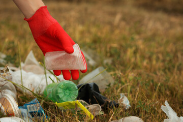 Fototapeta premium Woman in gloves collecting garbage in nature, closeup