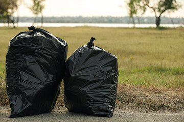 Trash bags full of garbage on pavement outdoors